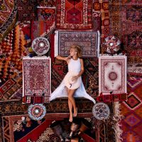 Beautiful happy girl in a long white dress laying on the carpet